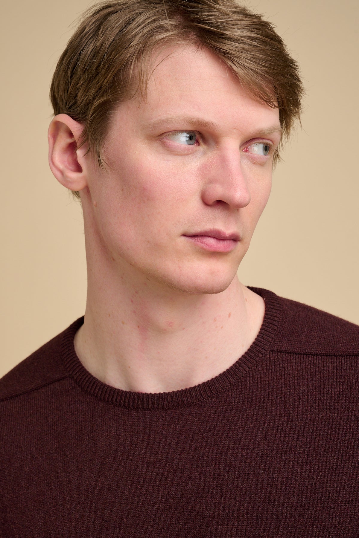Man wearing a brown sweater against a beige background