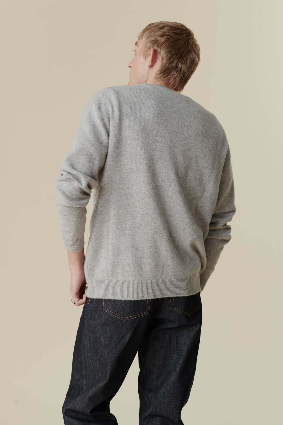 
            the back of white male, knee up, wearing lambswool crew neck in light grey