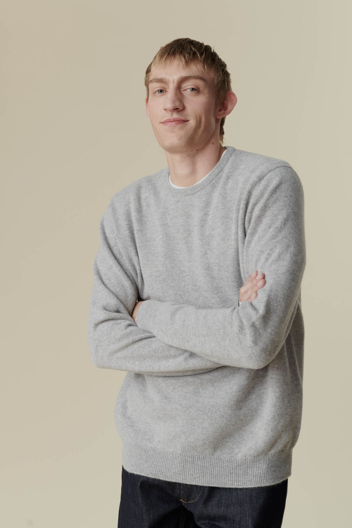 
            Male wearing lambswool crew neck in light grey, male has arms folded facing towards the camera.
