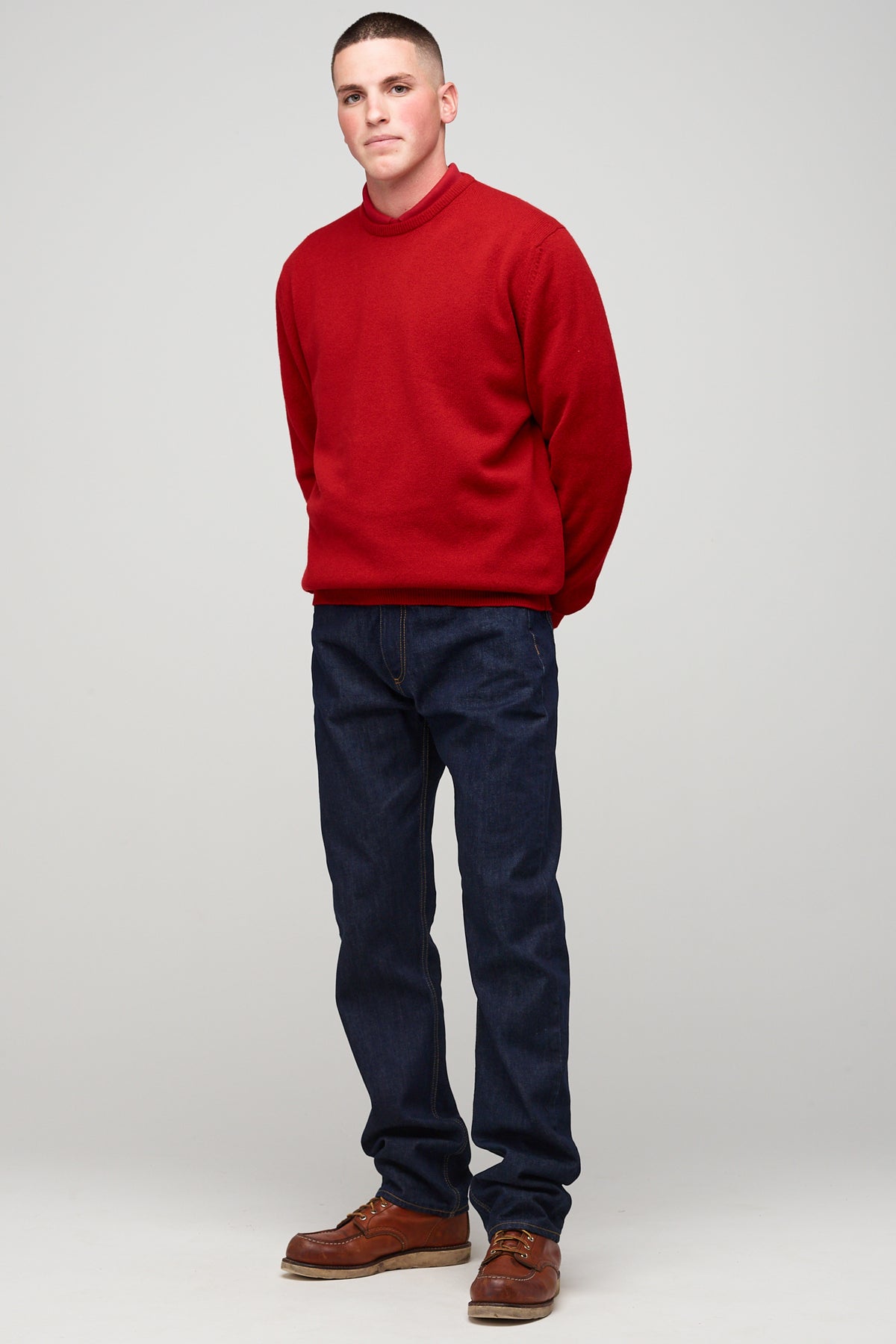 Brunette, white male wearing men's Lambswool Crew Neck in red styled with denim jean