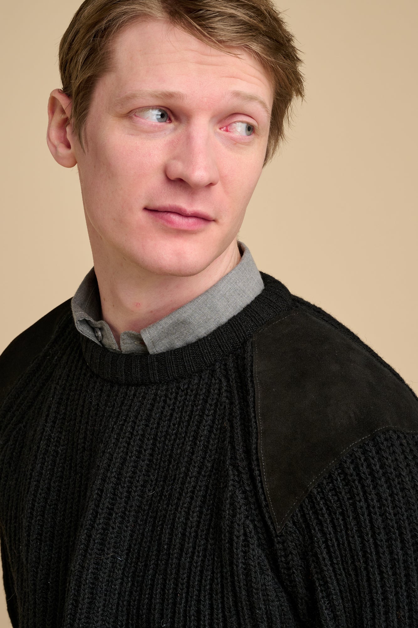 Man wearing a black sweater with a beige background