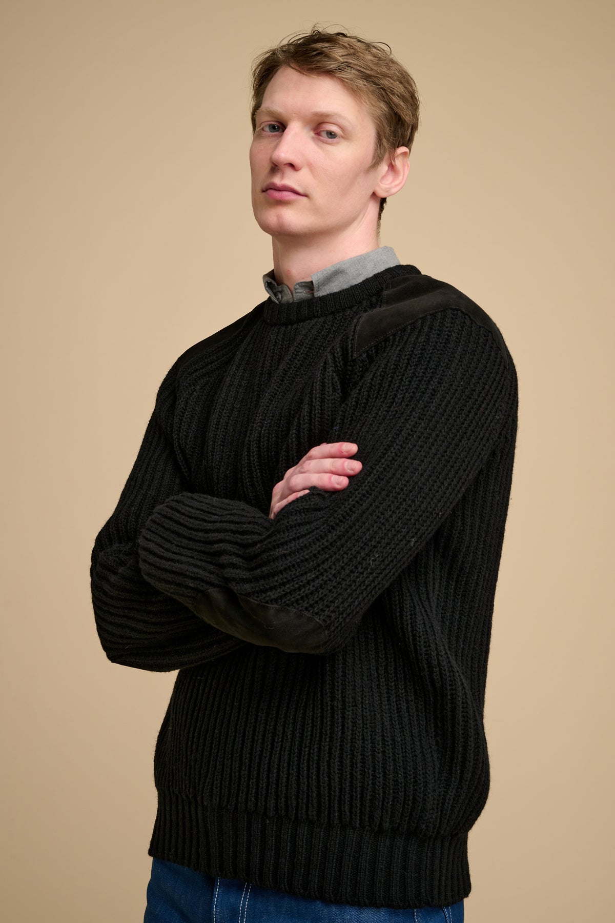 Man wearing a black sweater against a beige background