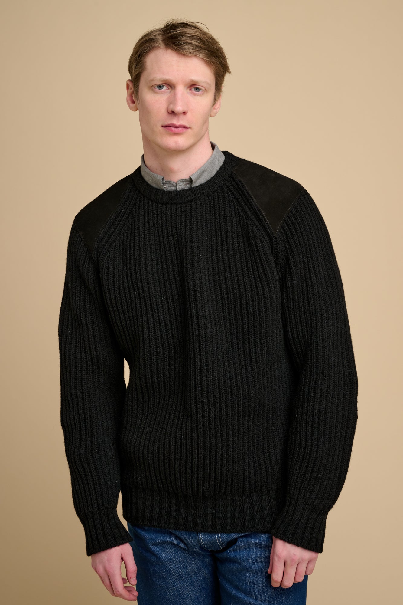 Man wearing a black sweater against a beige background.