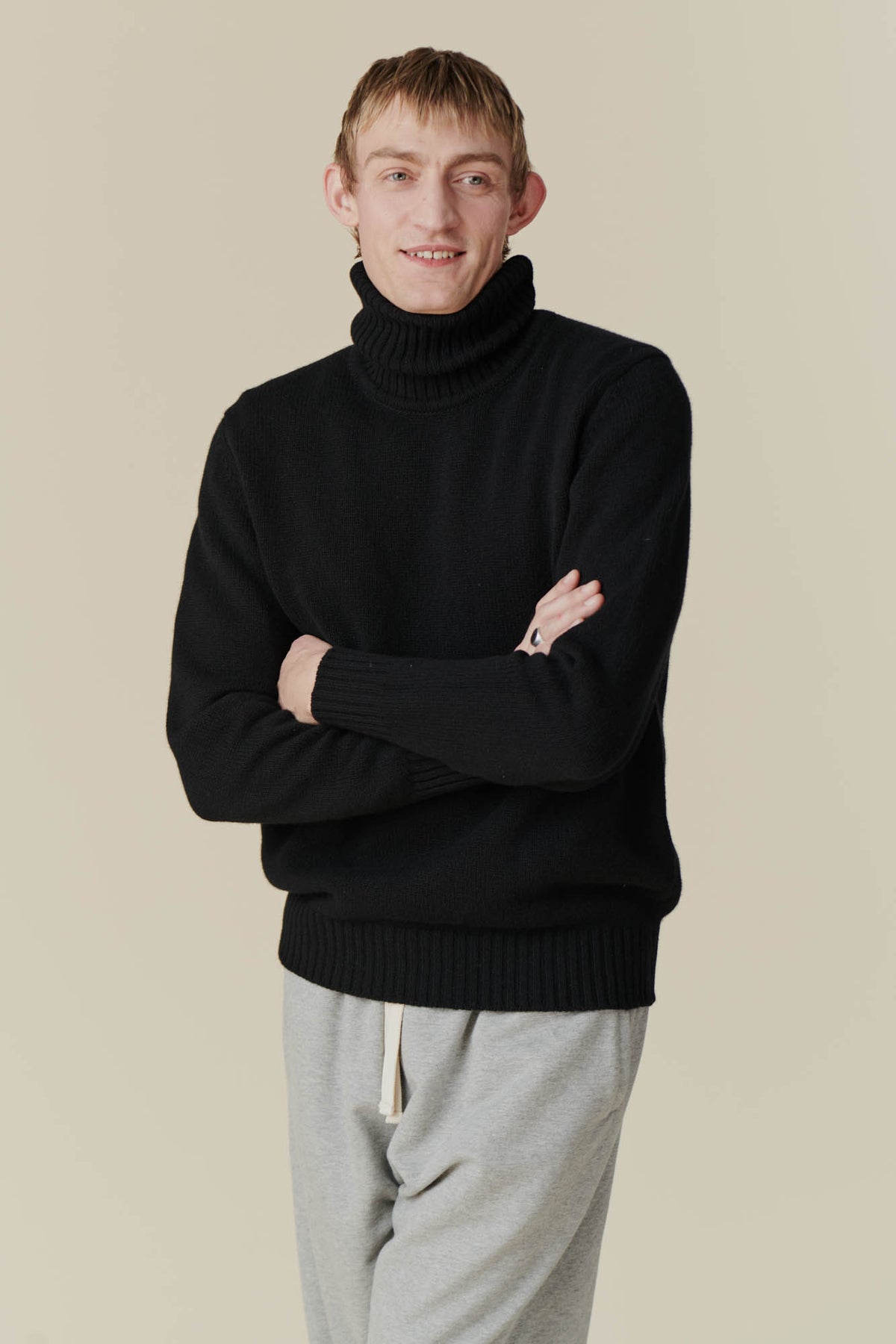 Smiley, white male with arms crossed wearing lambswool roll neck in black.