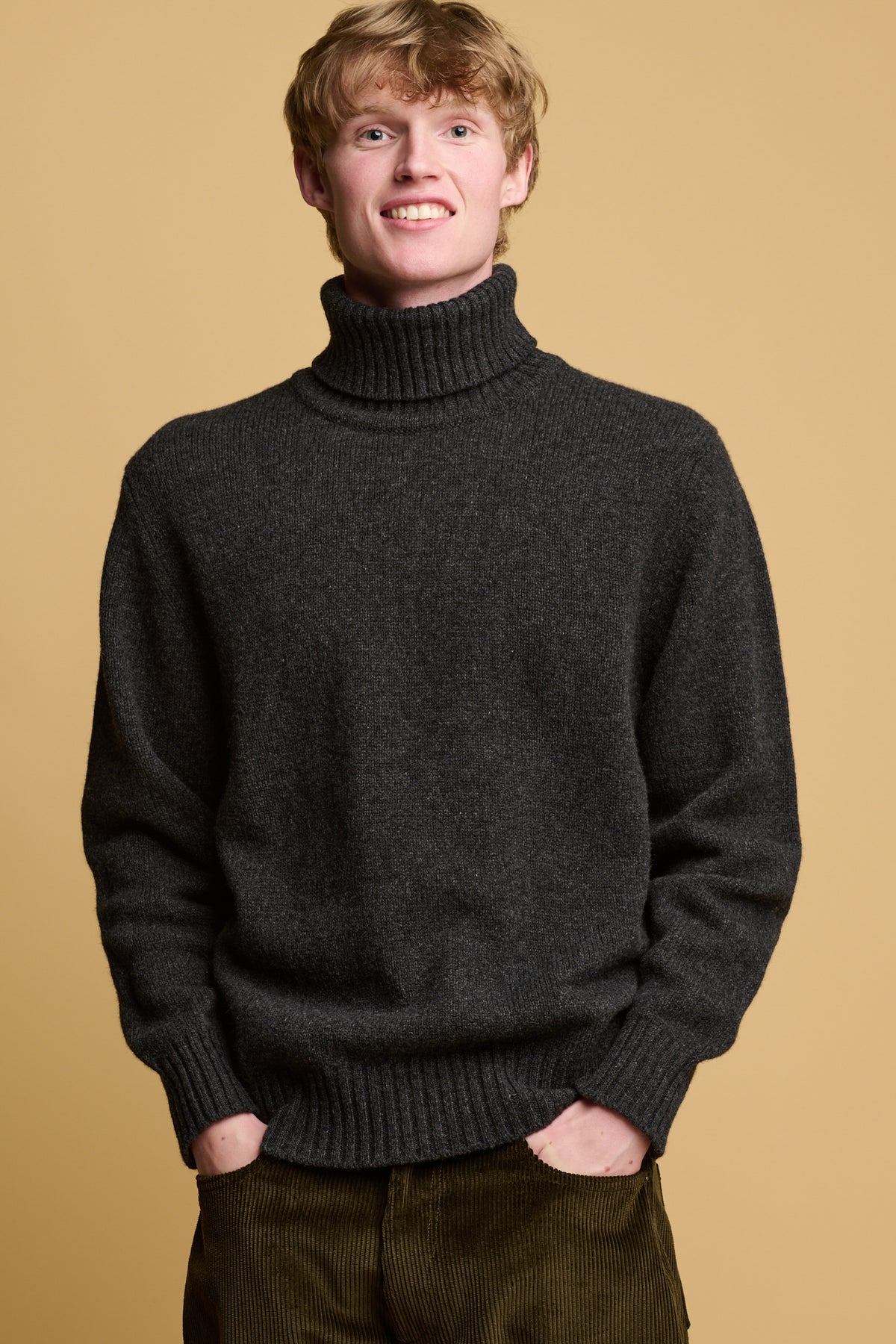 Thigh up image of male wearing lambswool roll neck in charcoal