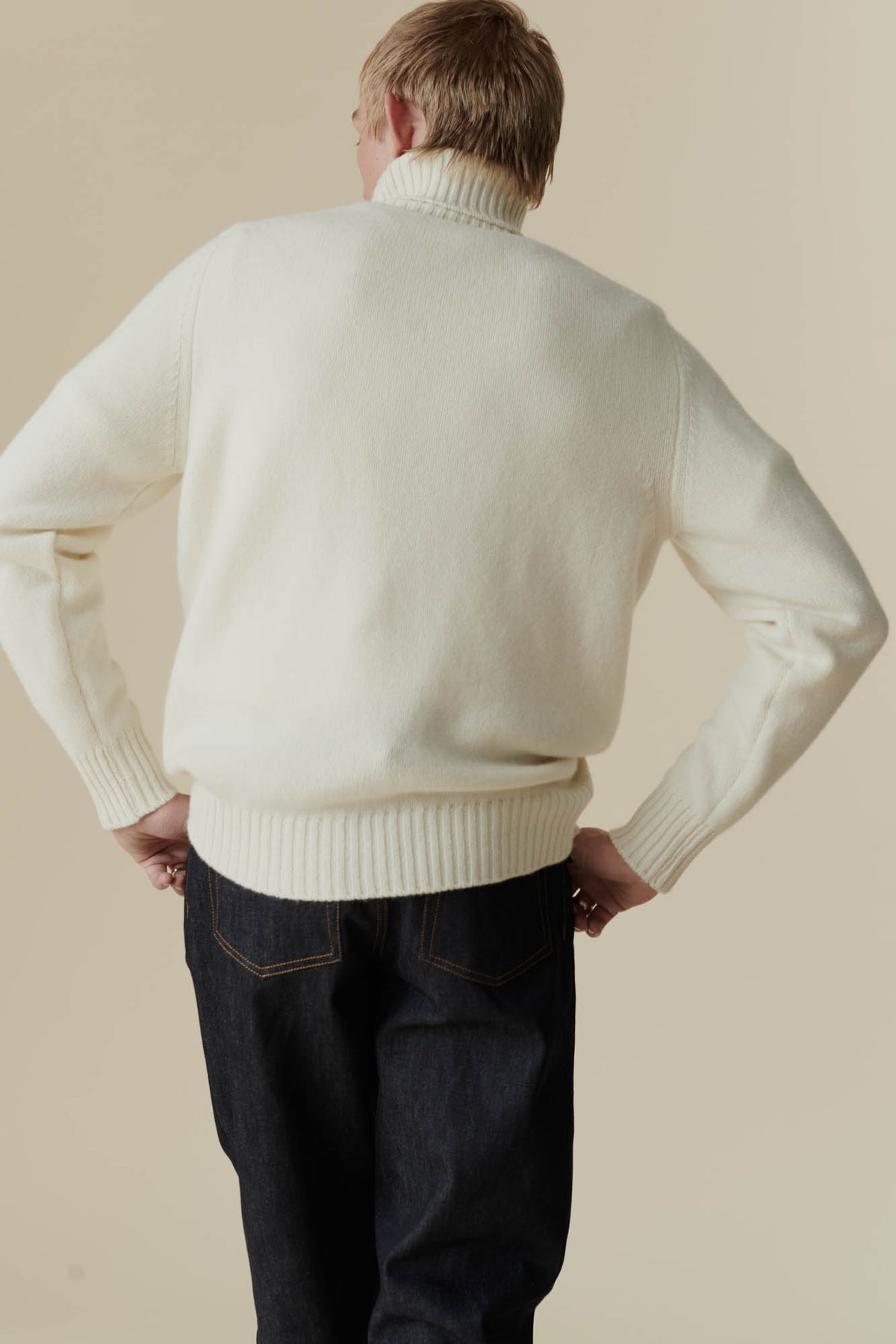 
            Thigh up shot of white male from behind, wearing lambswool roll neck in ecru
