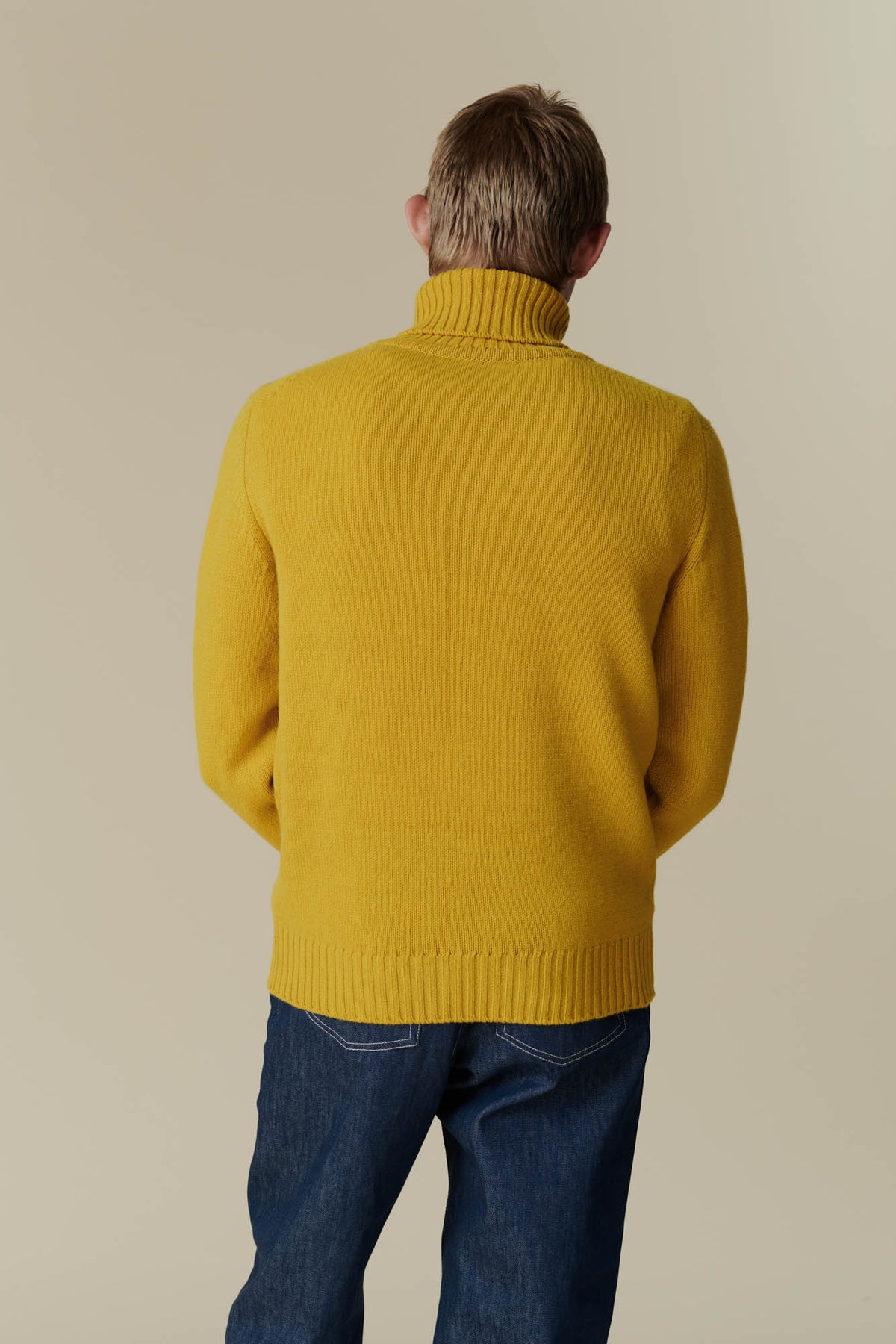 
            Behind shot of male in mustard lambswool roll neck.