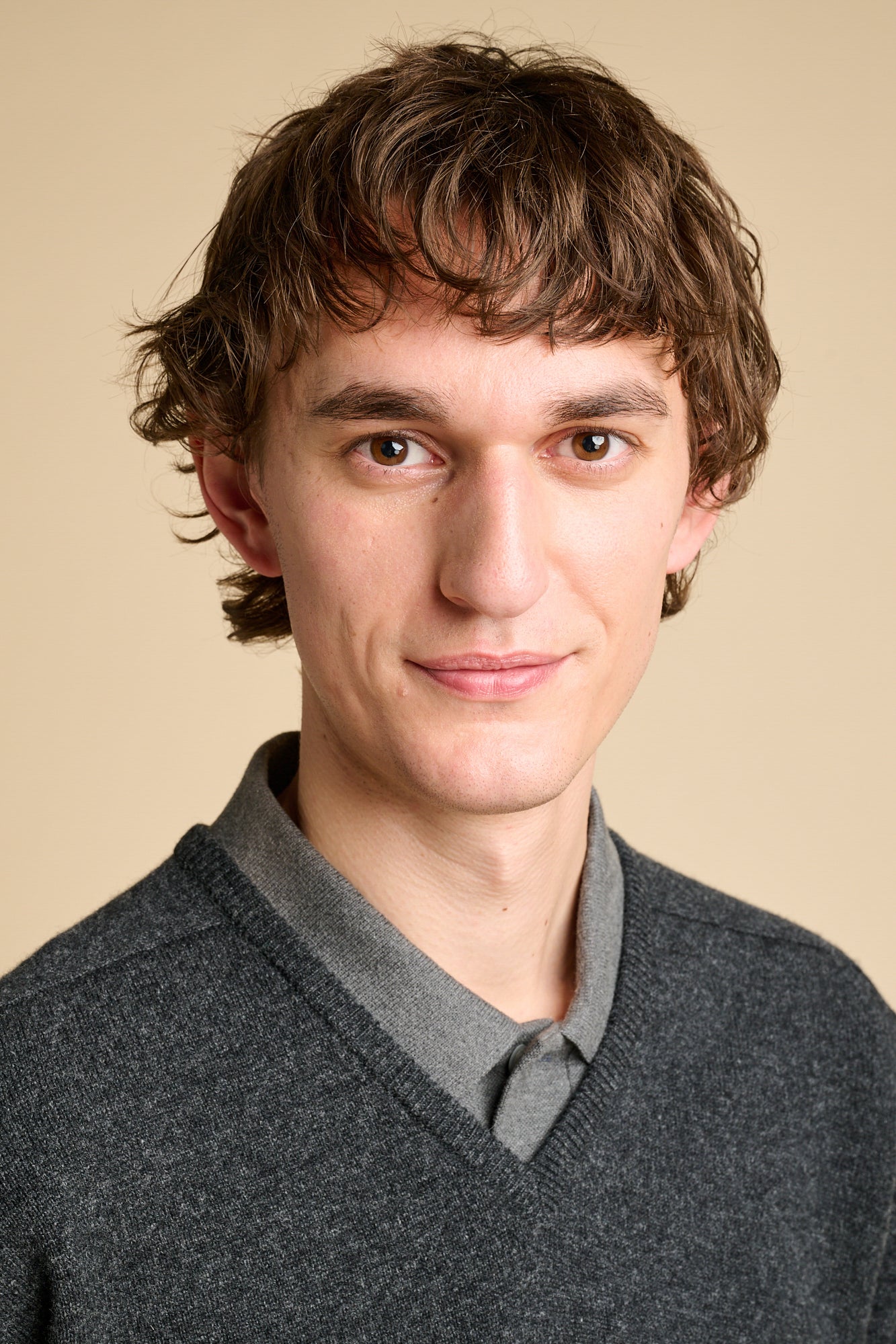 A man wearing a charcoal marl lambswool v neck jumper over grey polo shirt