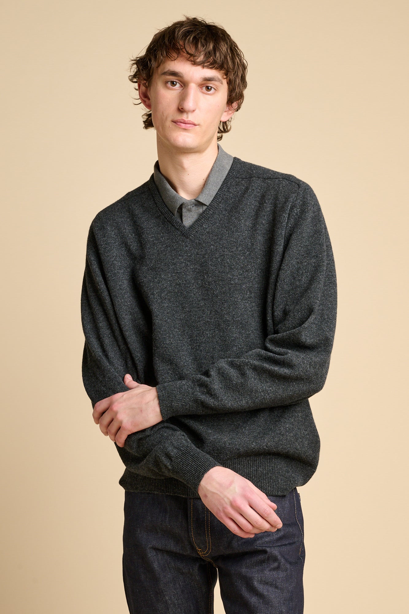 A man wearing a charcoal marl lambswool v neck jumper over grey polo shirt