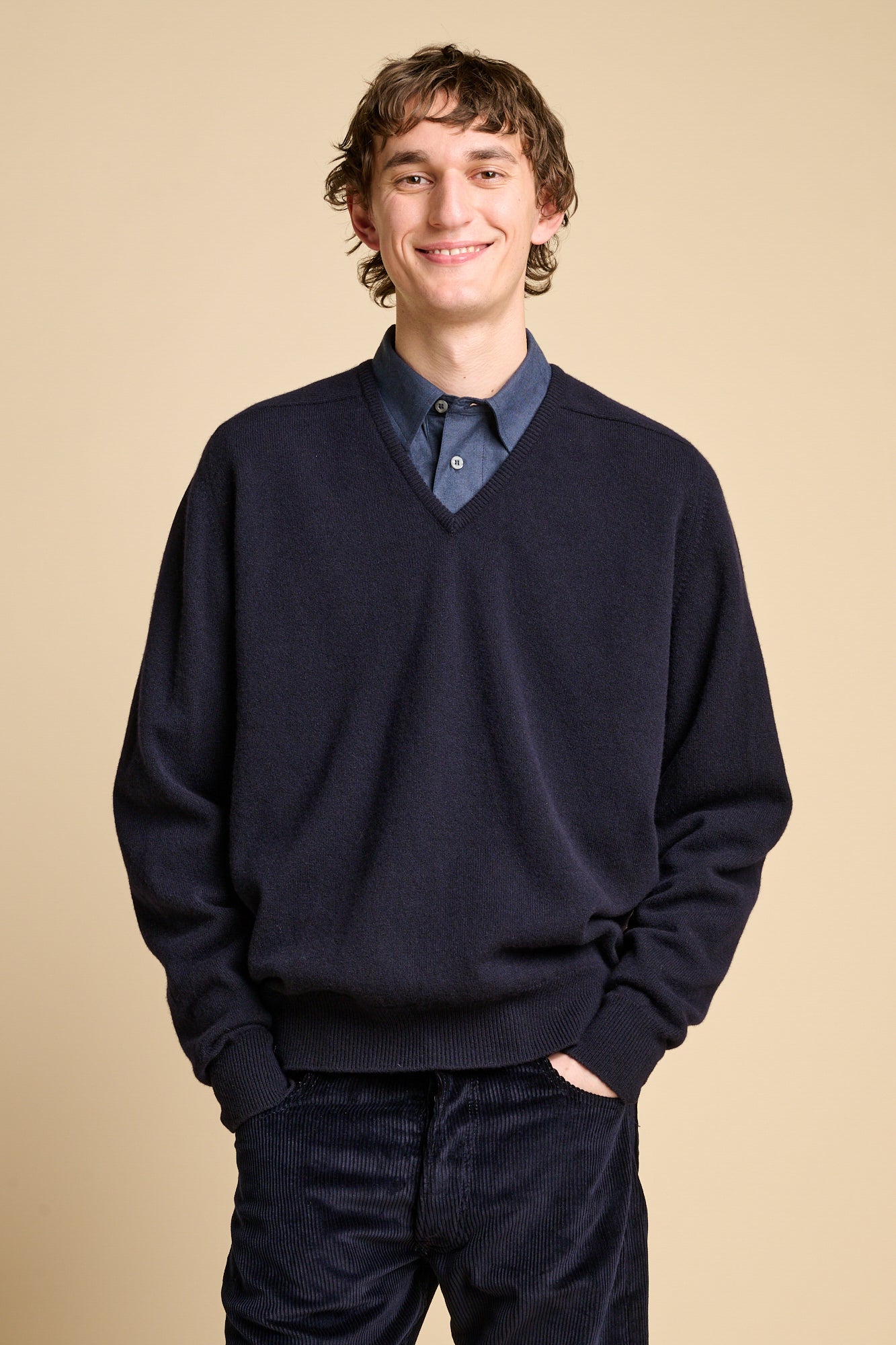 Male wearing lambswool v neck jumper in navy over shirt.