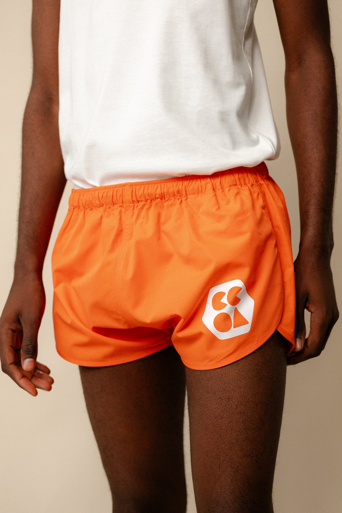 
            Image showing black male from shoulder to knee wearing men&#39;s lightweight running short plastic free in flame red with white CCOA logo