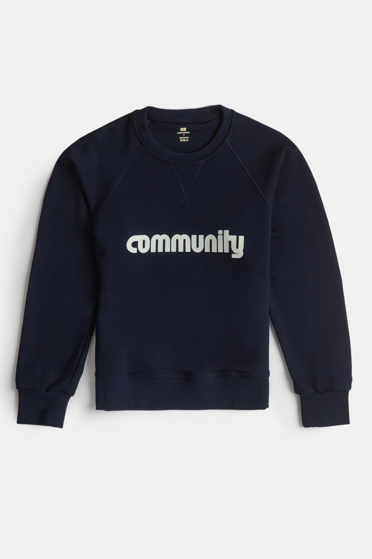 
            Flatlay product shot of men&#39;s logo raglan sweatshirt in navy with Community logo across the chest
