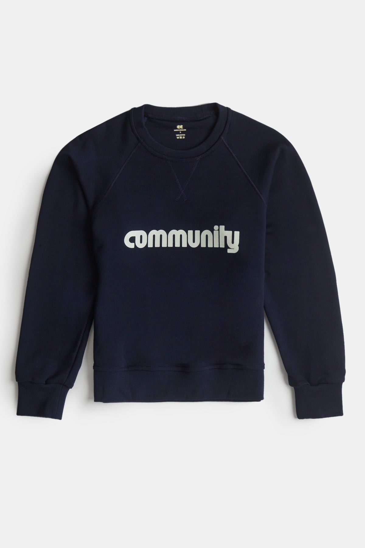 Flatlay product shot of men's logo raglan sweatshirt in navy with Community logo across the chest