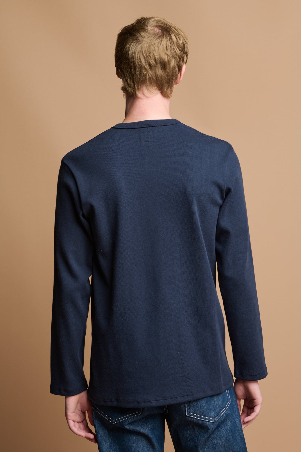 
            thigh up of the back of male wearing long sleeve 3 button henley top in blue