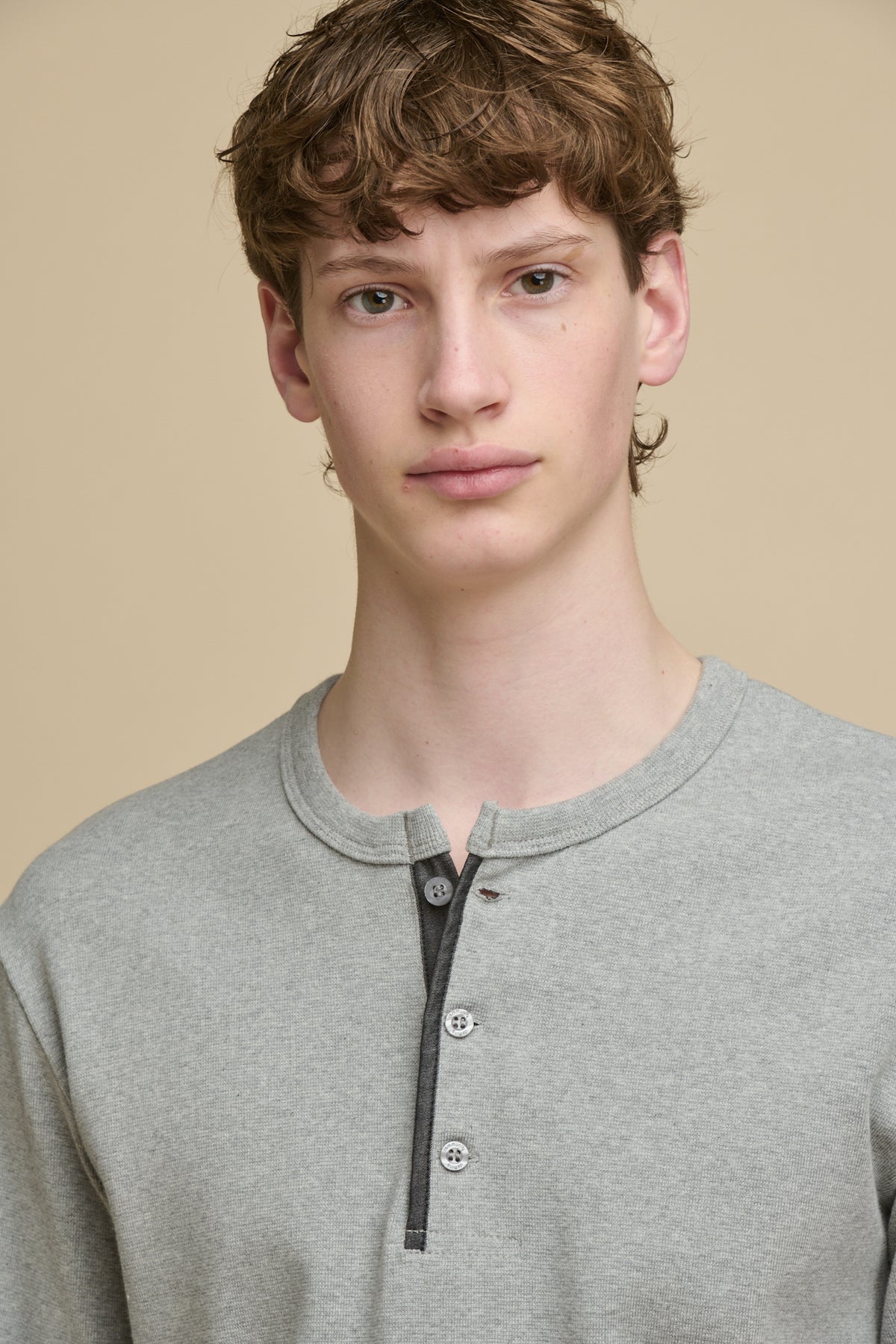 
            Portrait of male wearing long sleeve Henley top in grey marl with 3 button fastening