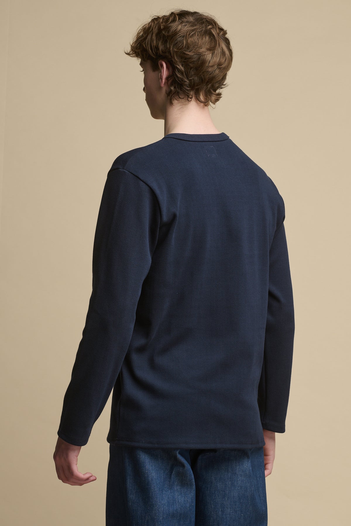 Thigh up image of the back of men's Long Sleeve Henley top in navy