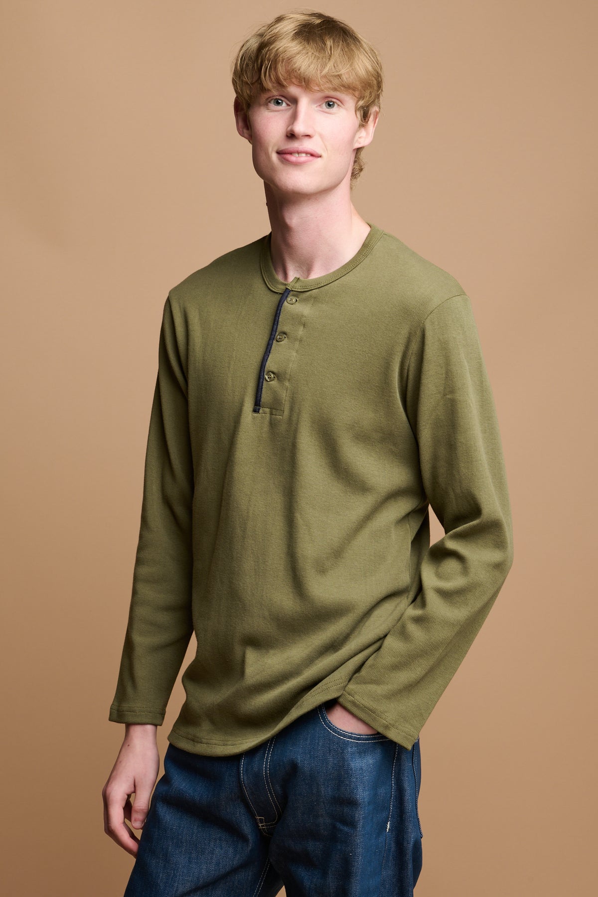Thigh up of male wearing long sleeve henley top in olive