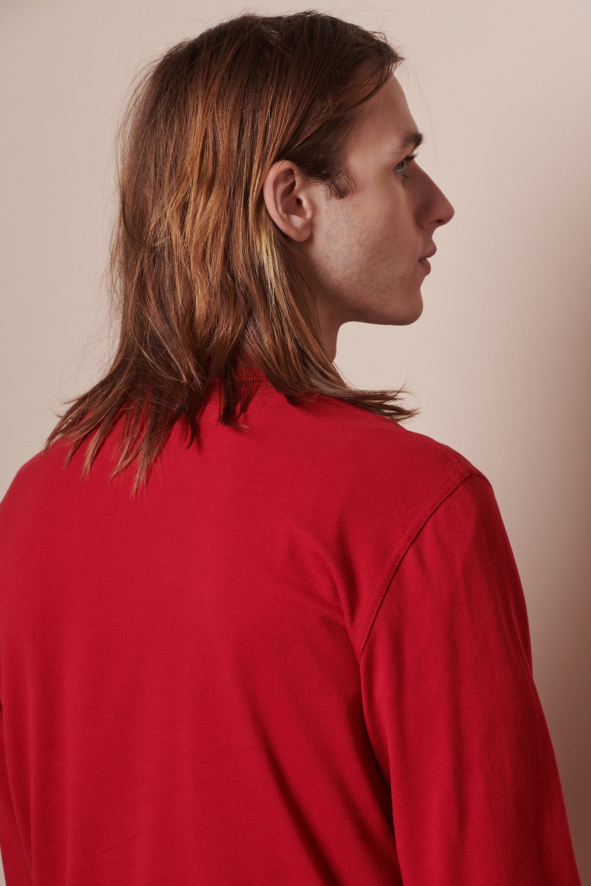 Back of male with shoulder length hair wearing long sleeve polo shirt
