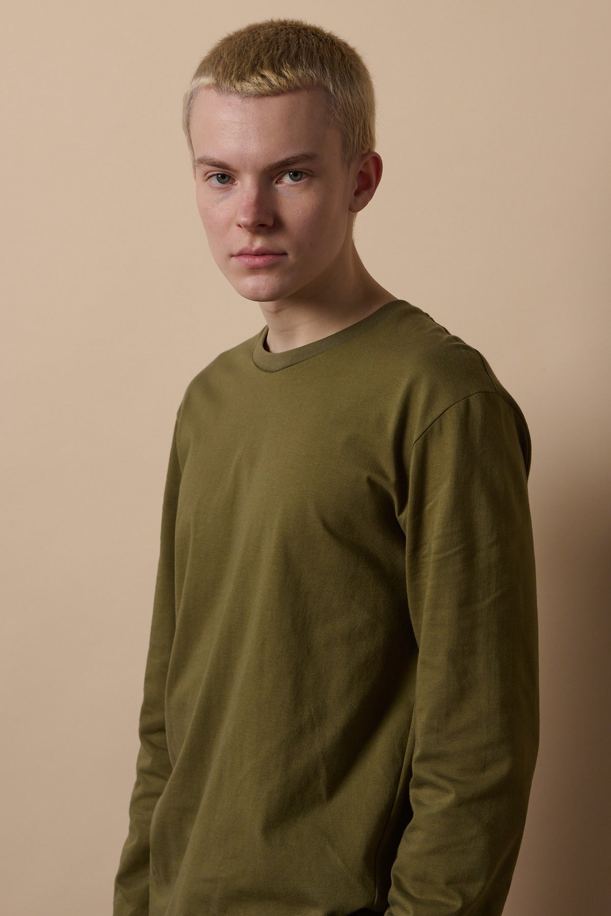 Hip up image of male wearing crew neck long sleeve t shirt in olive