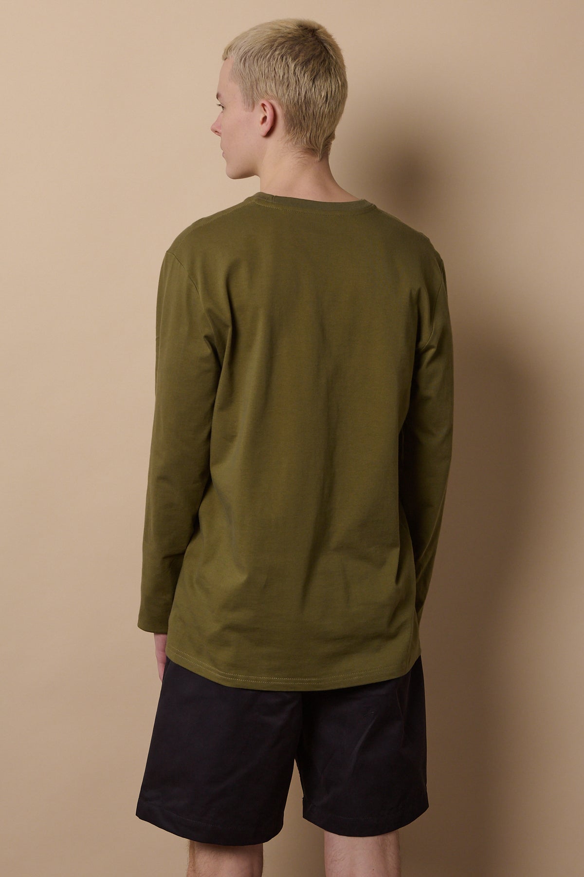 Back of white male wearing long sleeve t shirt in olive
