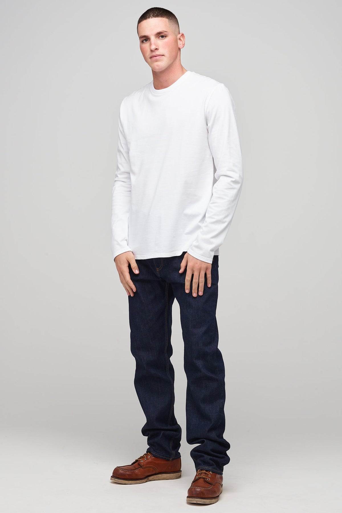 
            Brunet, white male wearing long sleeve t-shirt white over denim jeans and brown leather shoes
