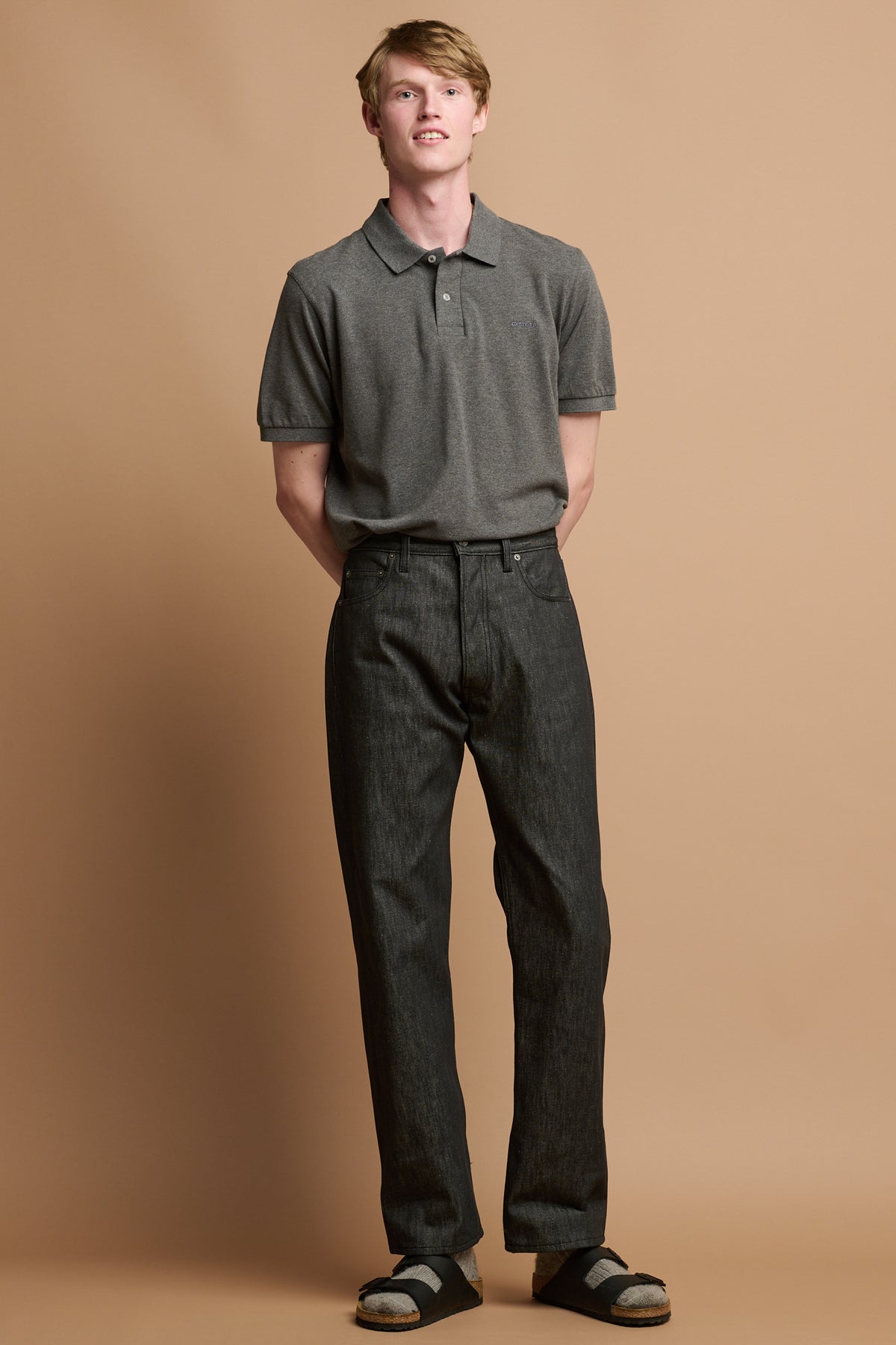 Male wearing black selvedge denim jeans with grey polo shirt.