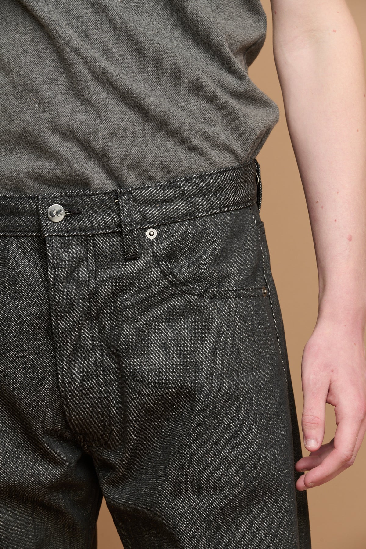Close up of the front pocket and belt loops of button fly arran jean in black with CC logo button