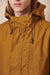 Side view of male wearing mountain parka in tan with hand in front pocket