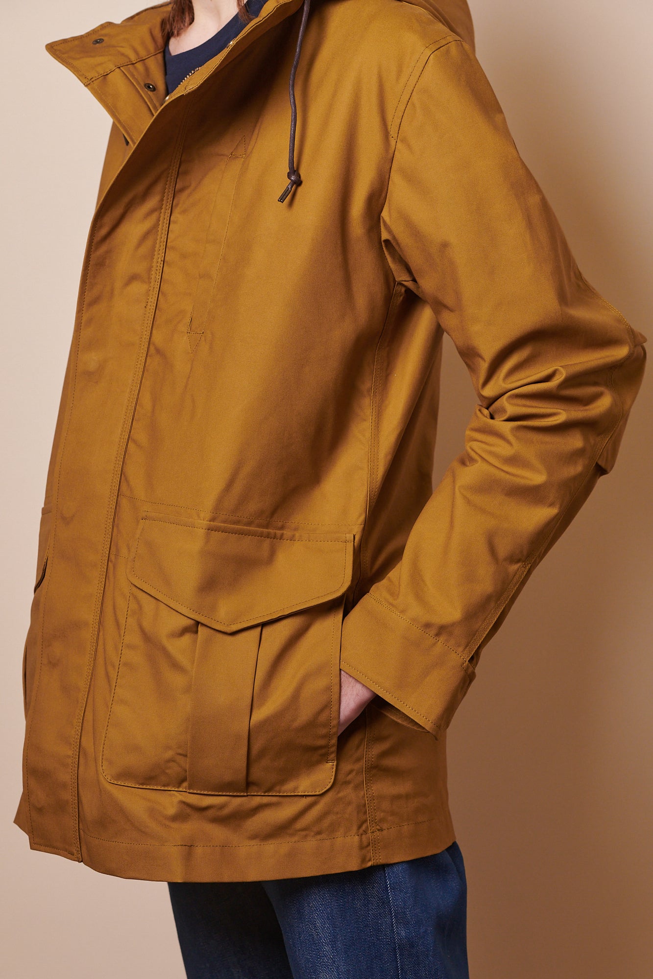 Side view of male wearing mountain parka in tan with hand in front pocket