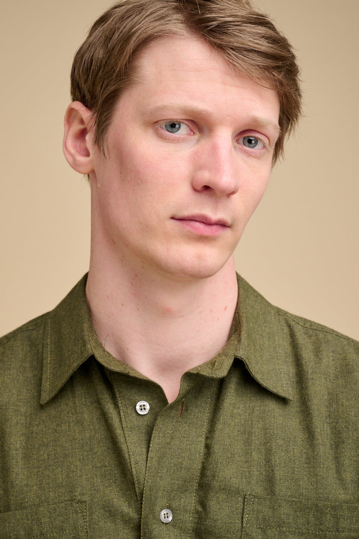 Man wearing an olive green brushed cotton shirt against a beige background.