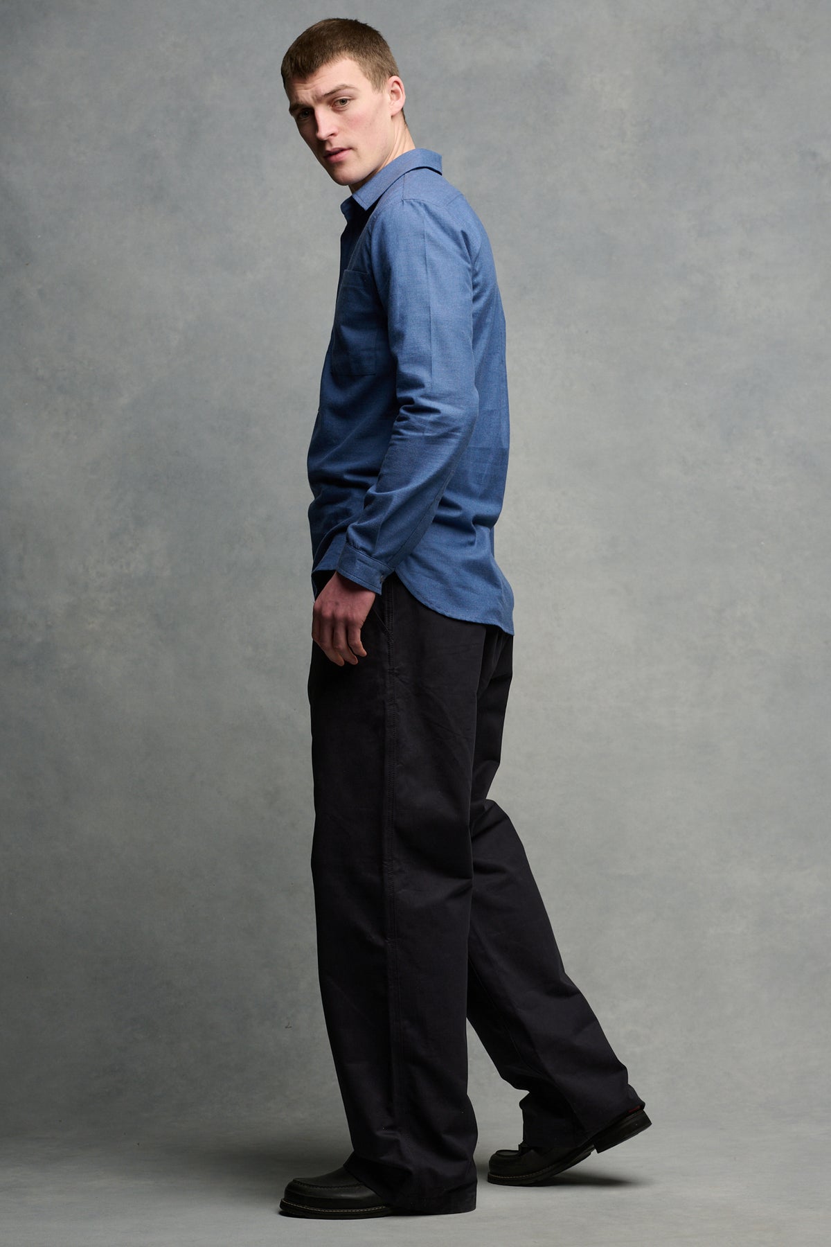 
            Full body image of the back and side of Oli shirt in RAF blue showing the curved hem over the men&#39;s field trousers in navy