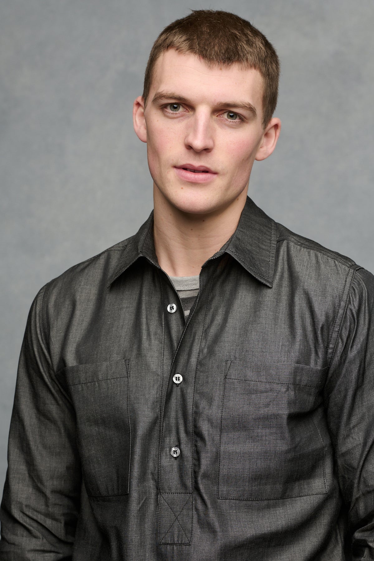 Waist up front of male wearing Oli denim shirt in black with the top two buttons undone, worn over Breton in charcoal and grey