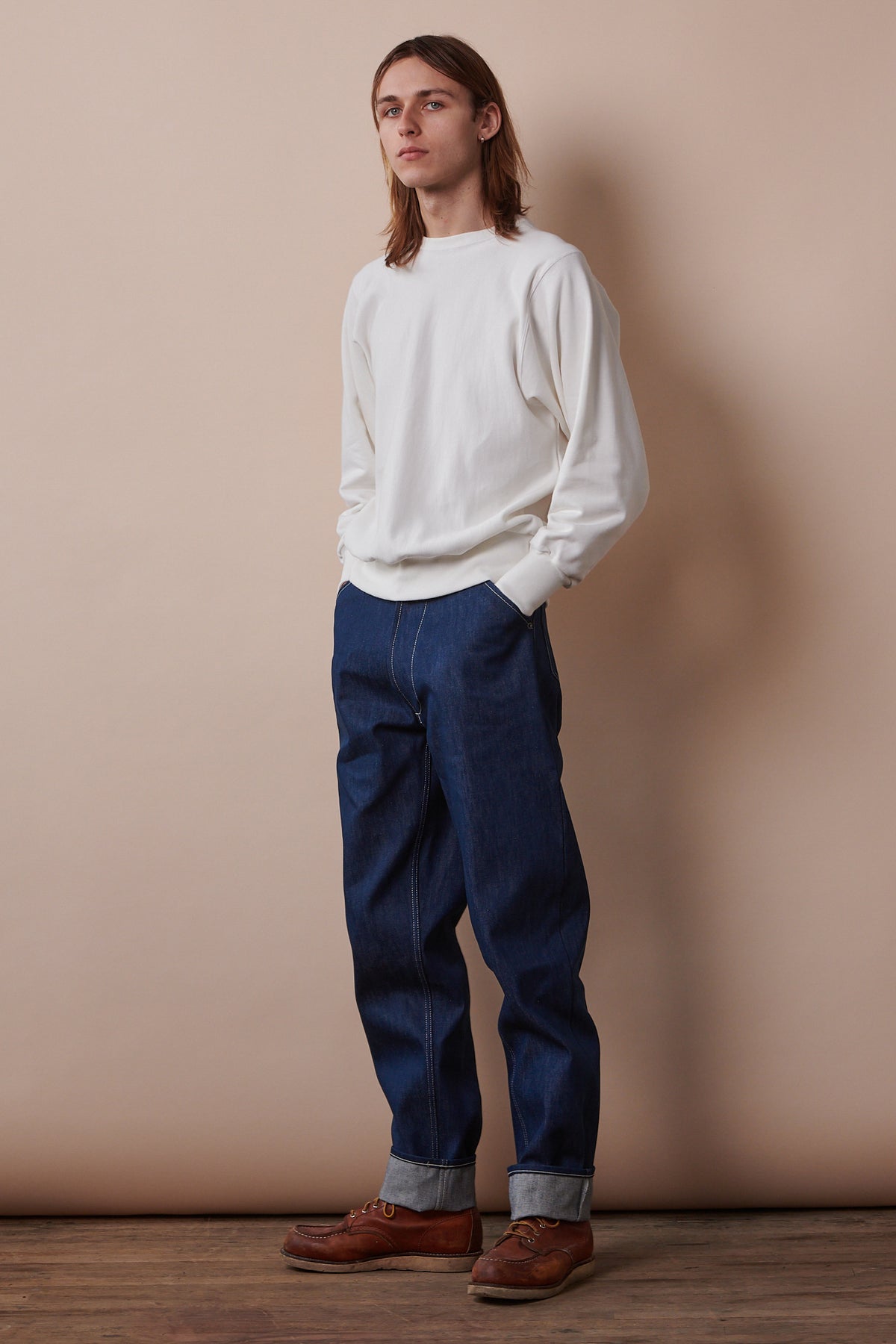 Full length image of male wearing 80s sweatshirt in bone paired with Chore Jeans in blue