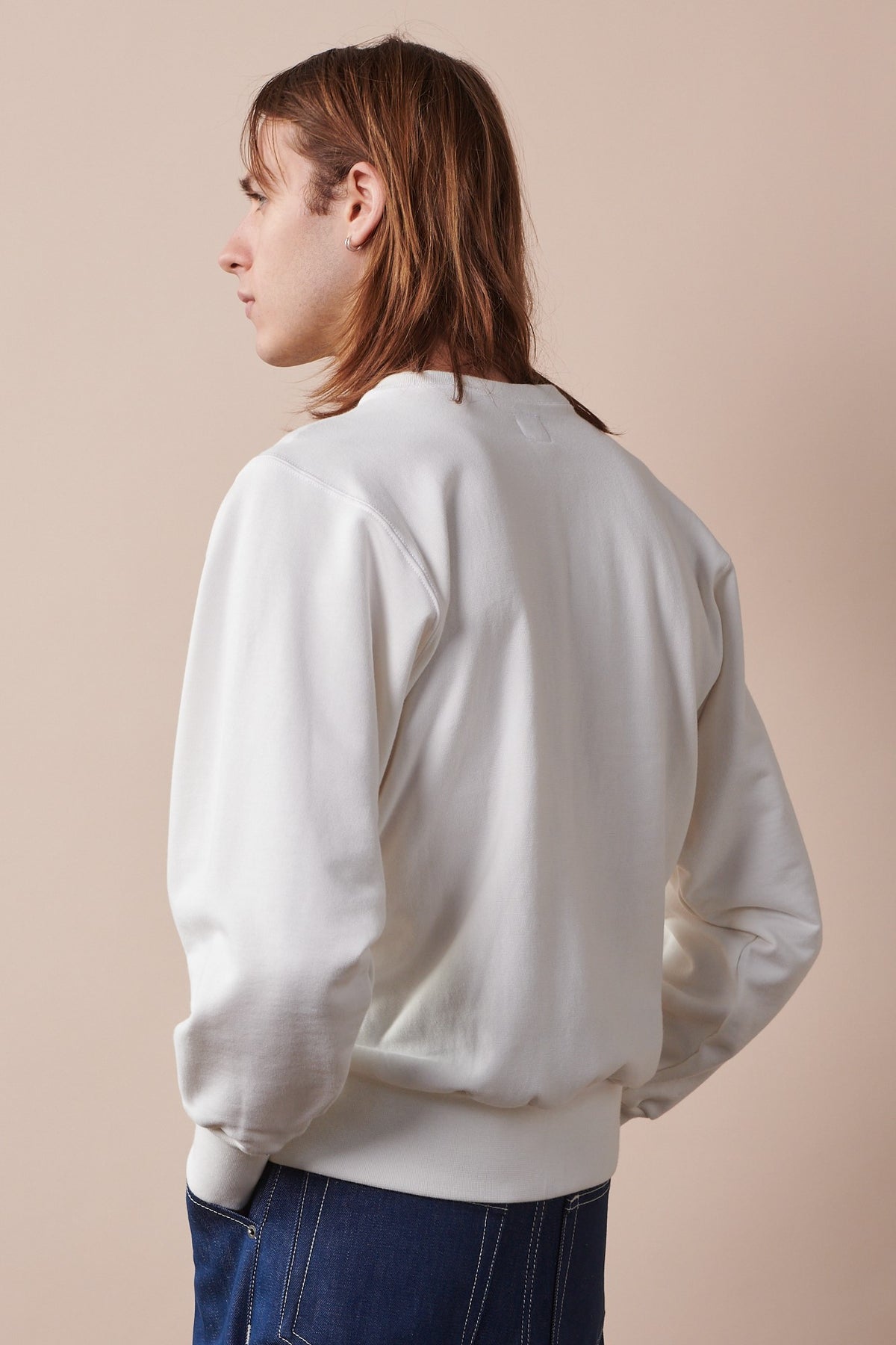 Thigh up image of the back of male with shoulder length hair wearing Oversized 80s Style Sweatshirt in bone