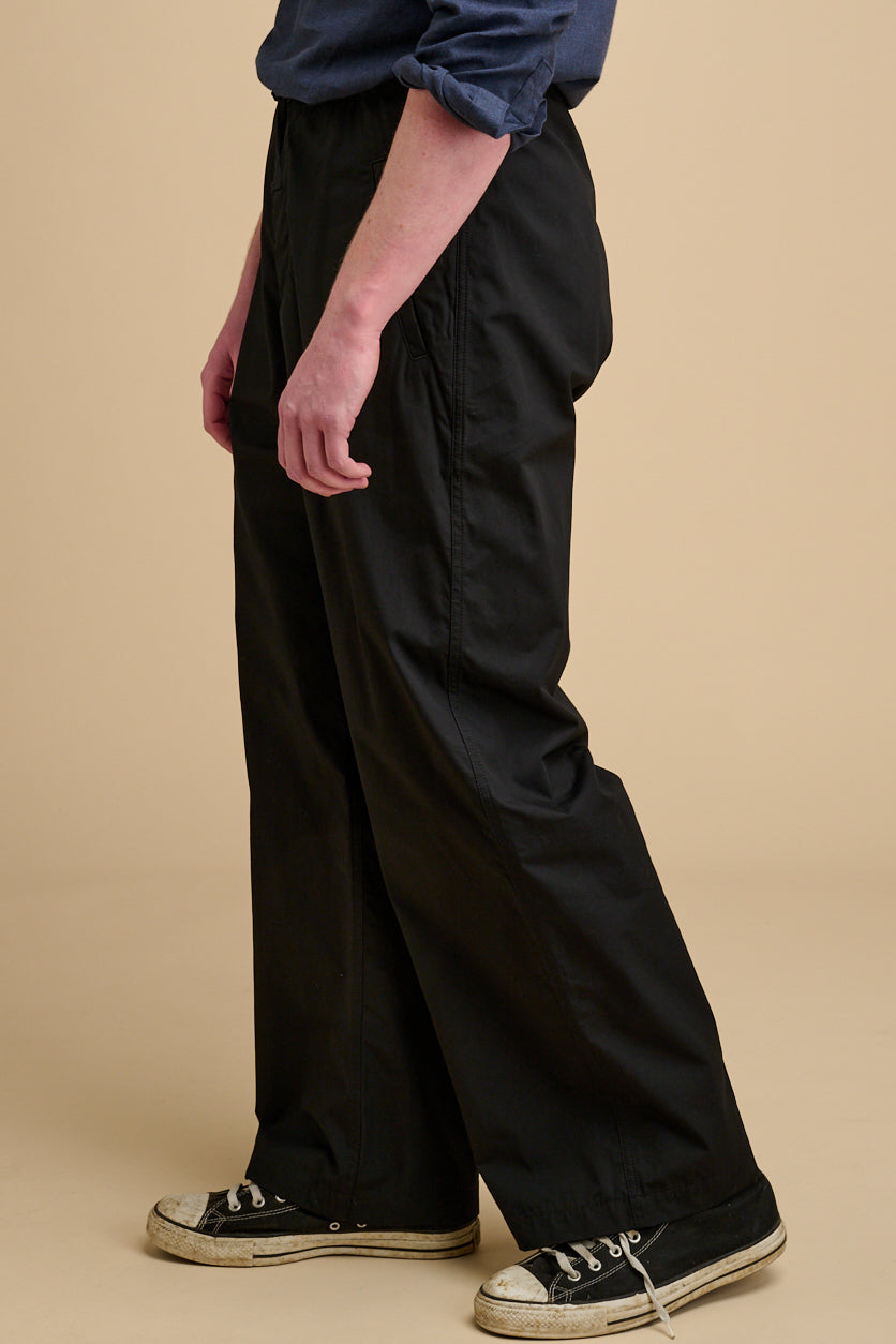 Man wearing black trousers on a beige background.