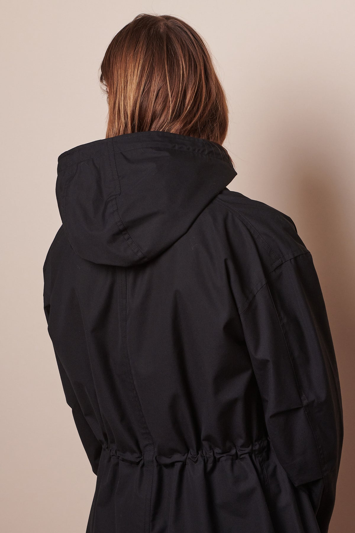 hip up of the back of male wearing black parka, adjustable waist drawstring
