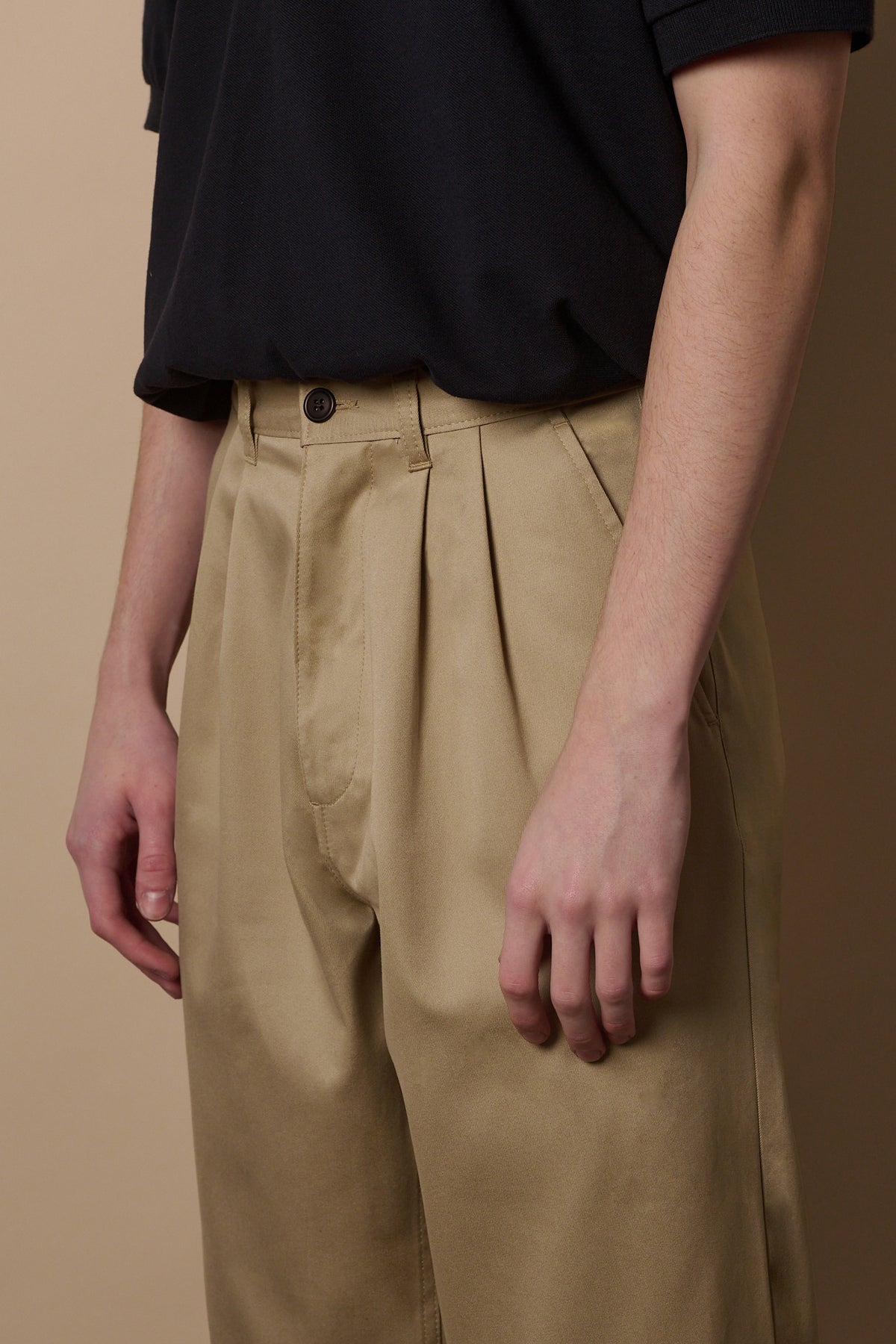 Detail of waistband front pocket on pleated chino in stone