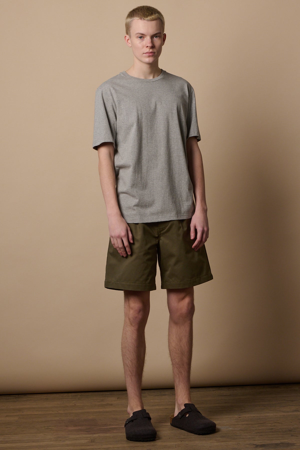 
            Full body image of male wearing pleated shorts in olive with short sleeve t shirt 