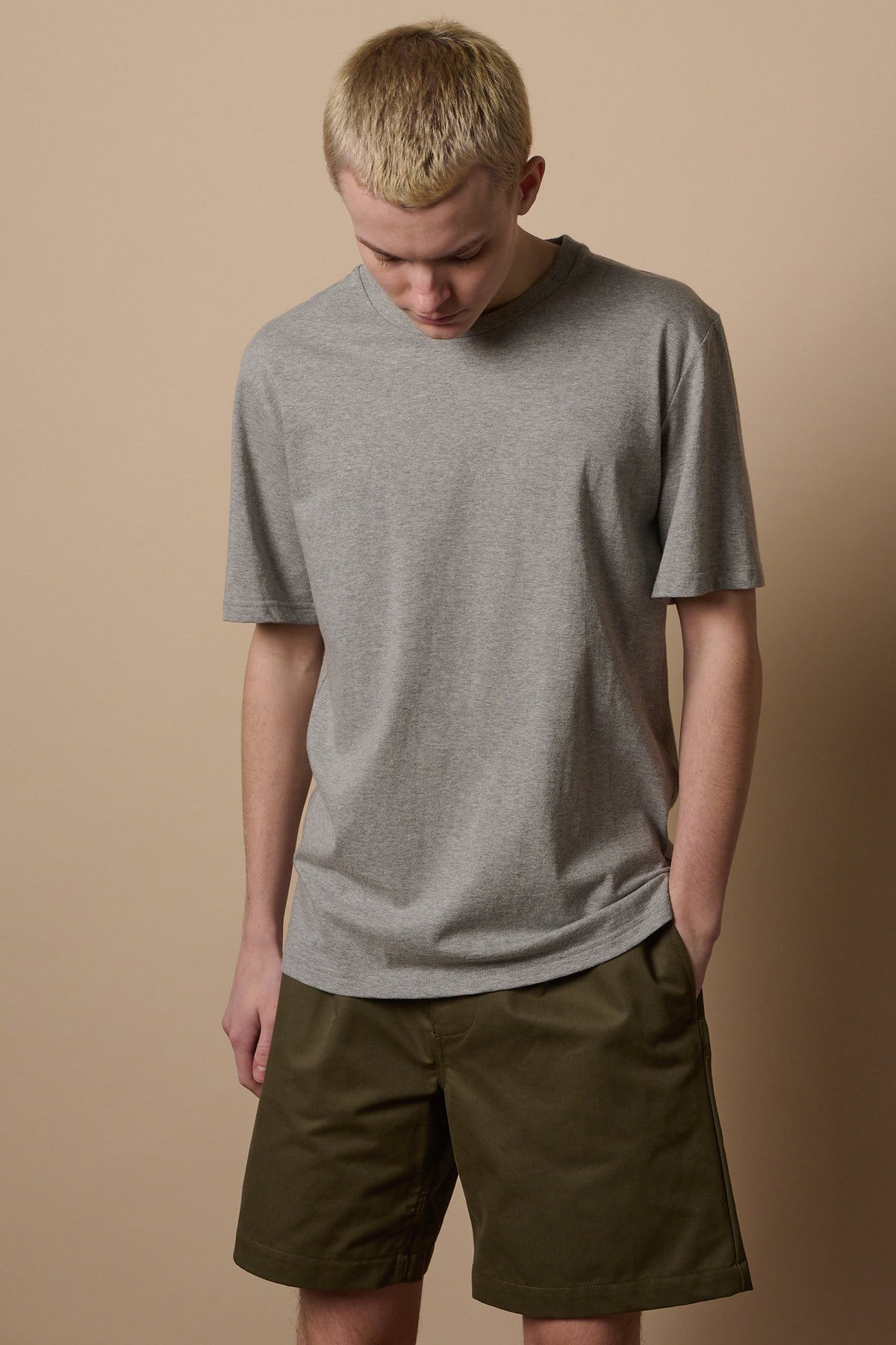 
            Knee up image of white make wearing pleated shorts in olive paired with short sleeve grey t shirt