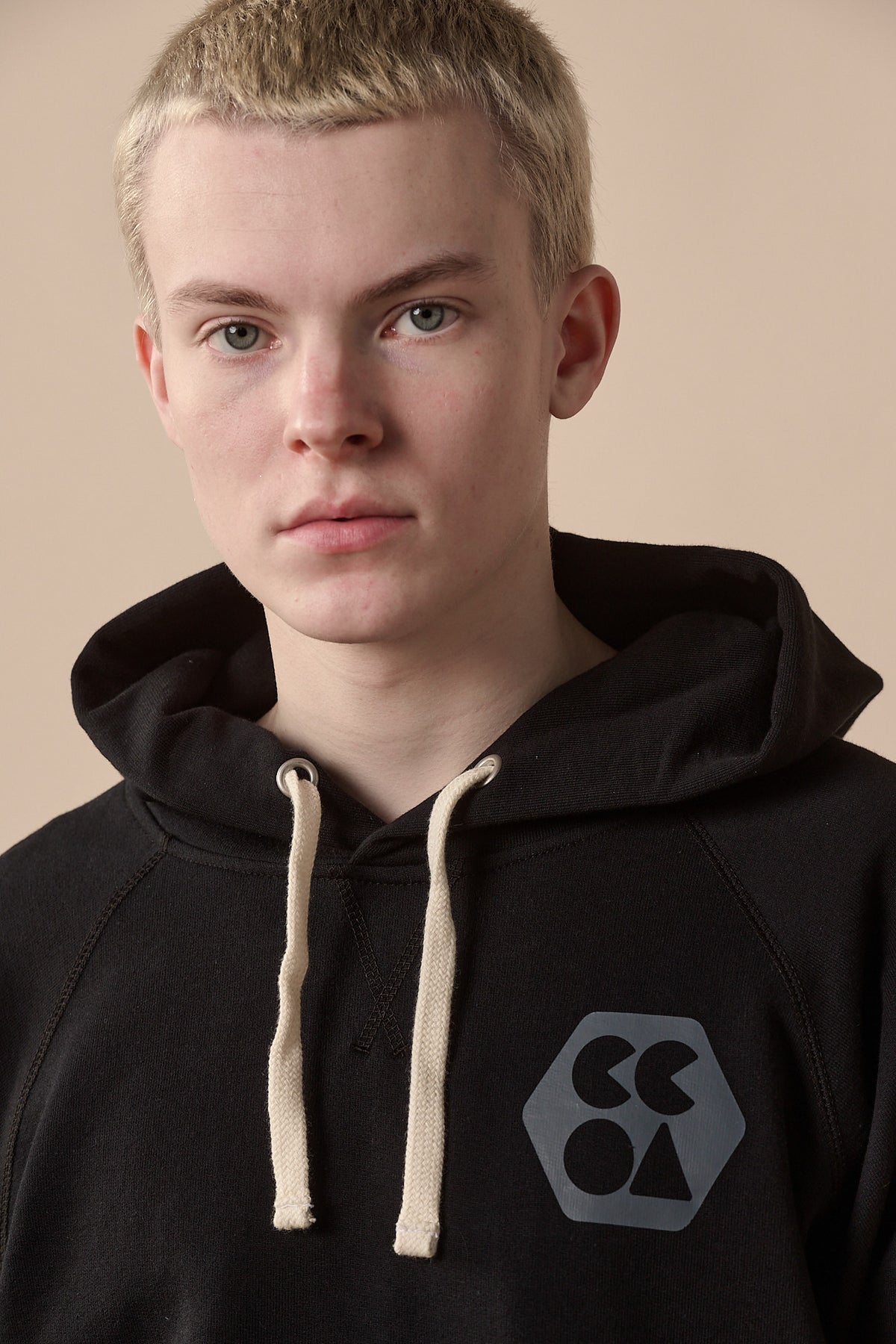 Portrait of male wearing raglan hooded sweatshirt plastic free in black with CCOA logo