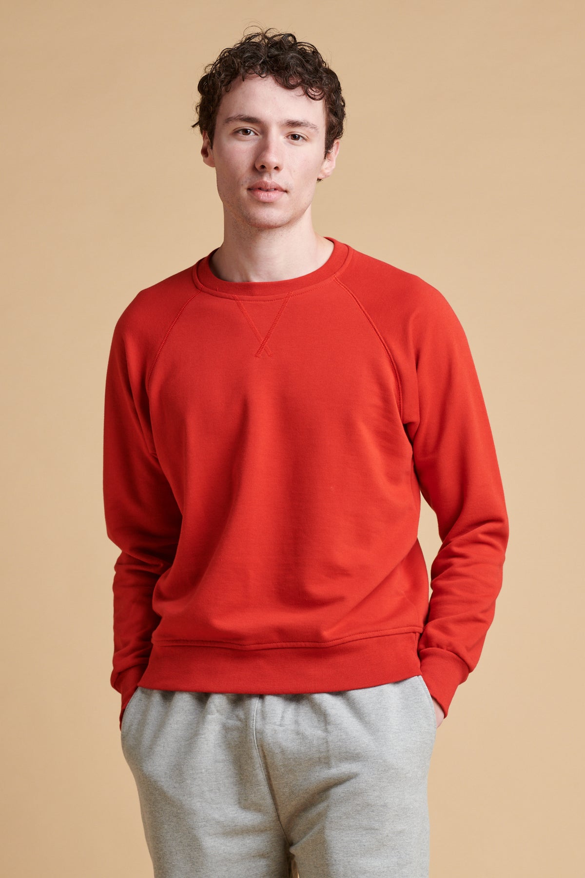 Thigh up of male wearing raglan sweatshirt in crimson.