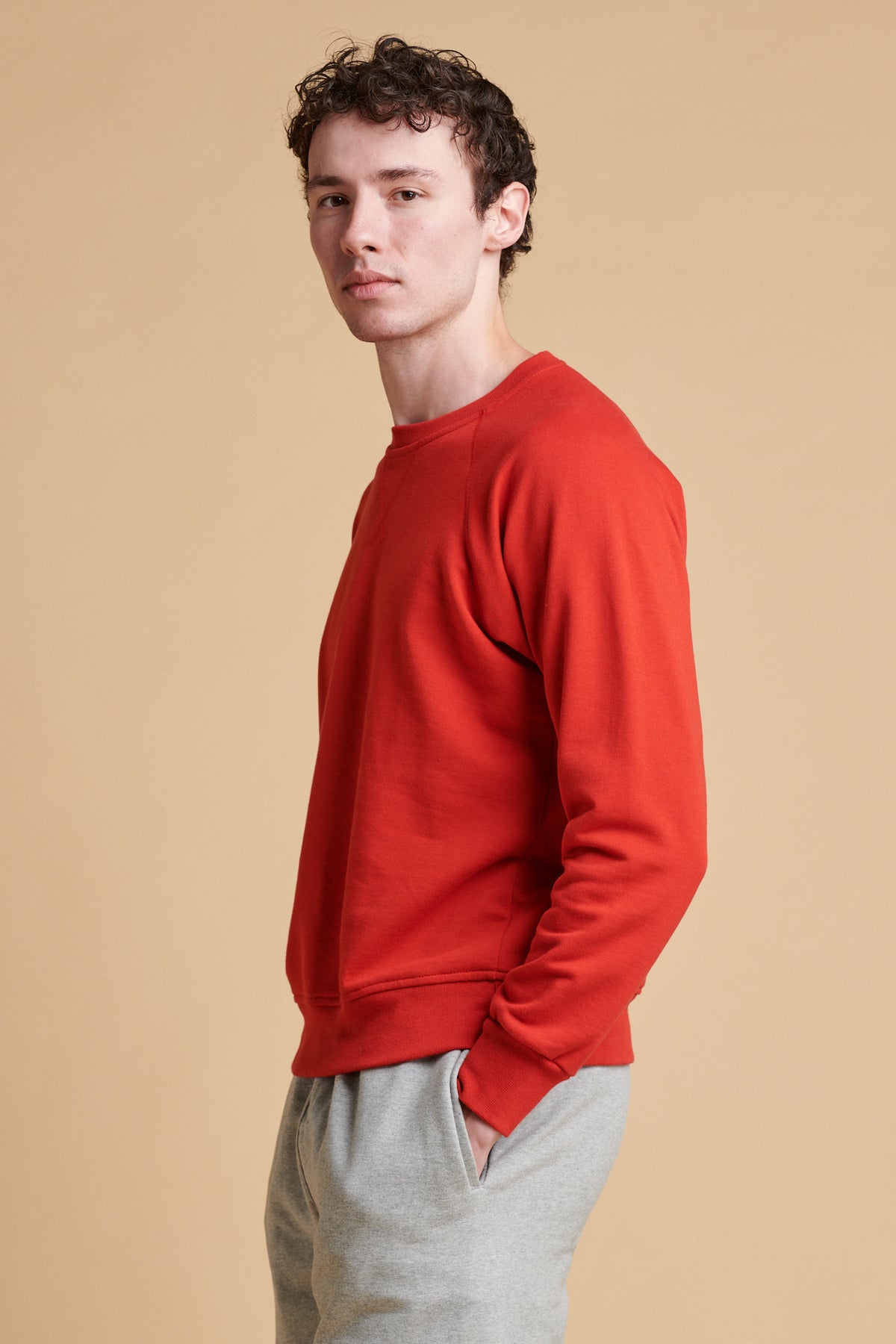 Thigh up of the side of male wearing raglan sweatshirt in crimson.