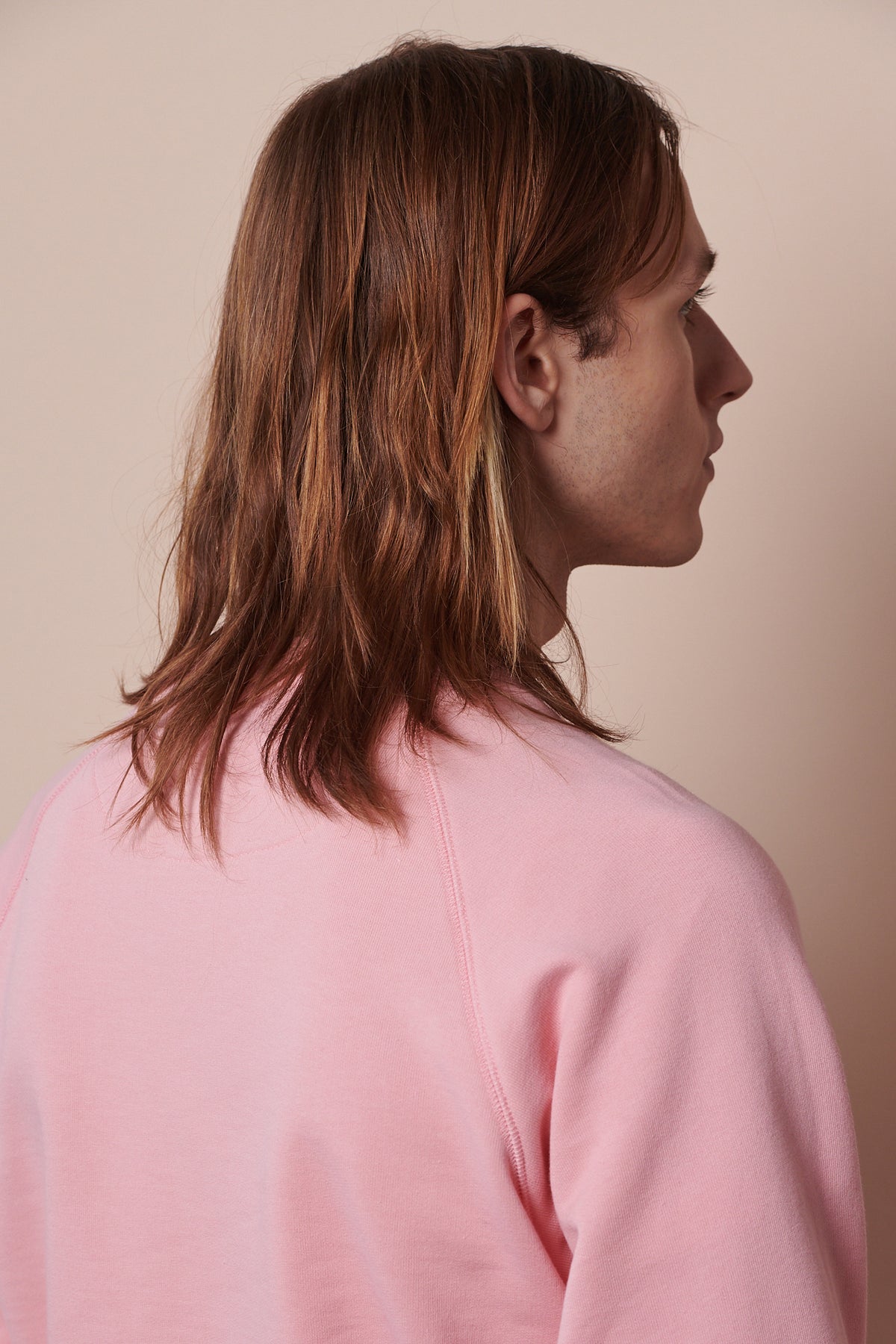 
            Back of male wearing raglan sweatshirt in pale pink