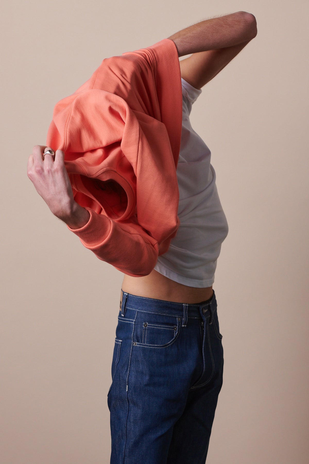 Image of male taking raglan sweatshirt jumper off body whilst leaving white crewneck t shirt on.