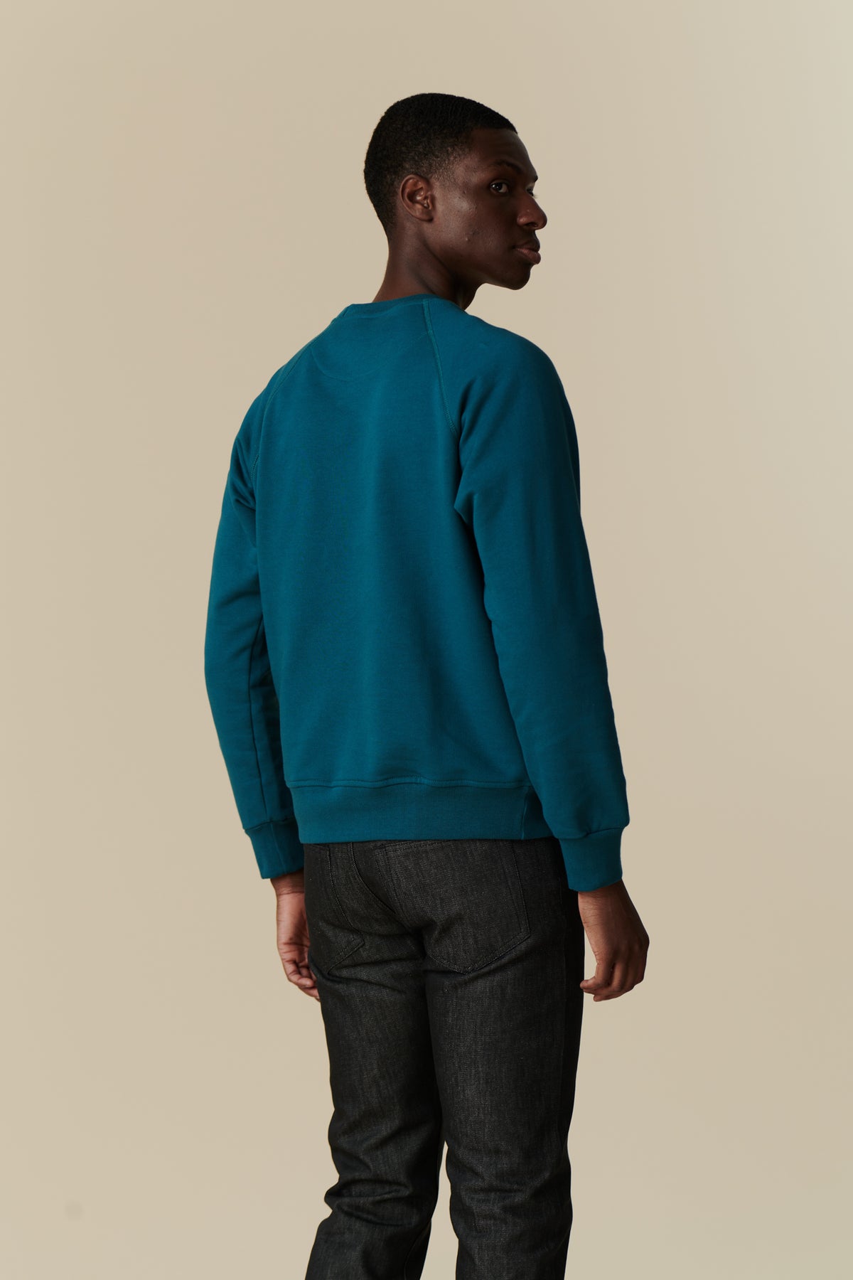 Back of male in men's raglan sweatshirt in teal