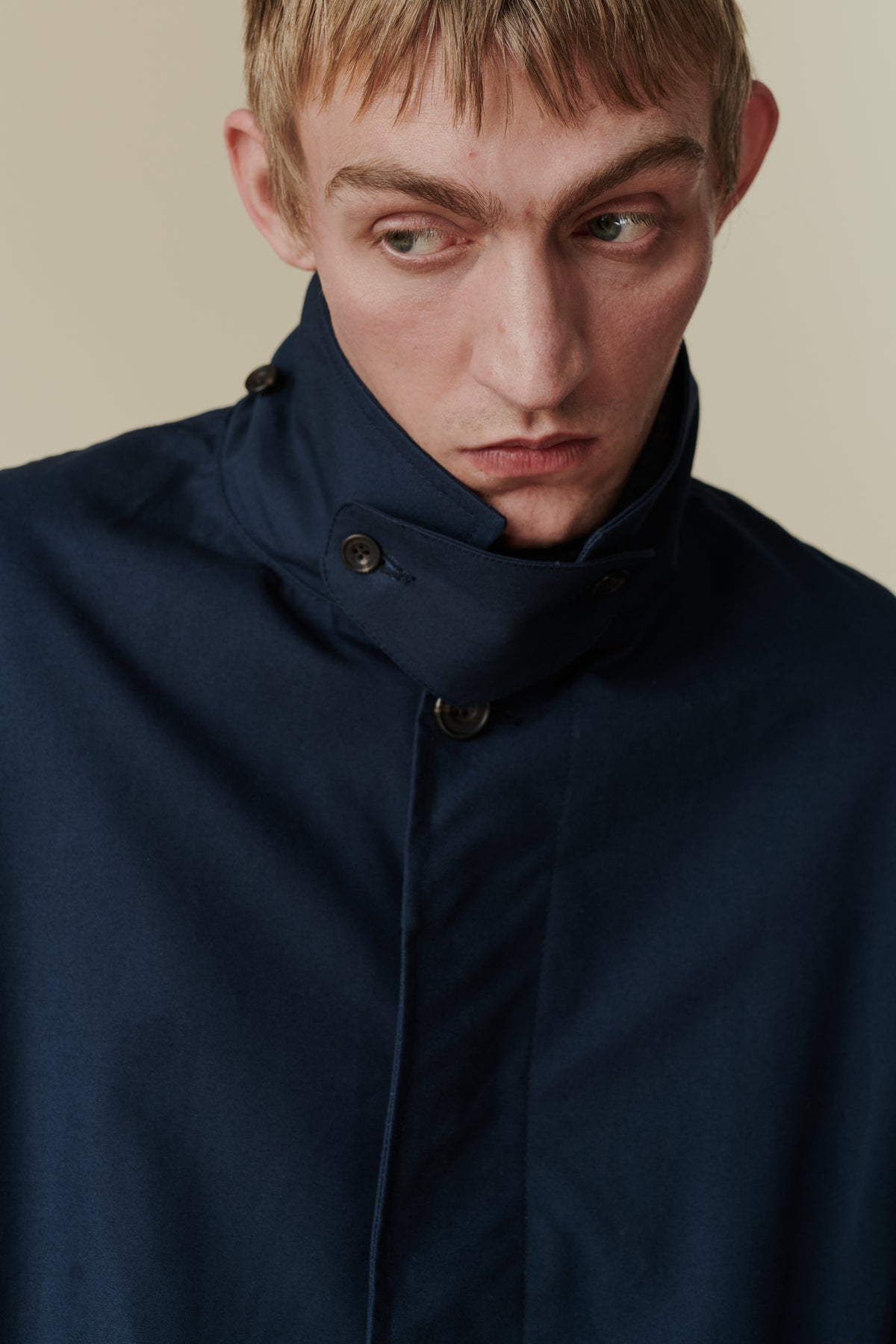 
            Chest up portrait of white male wearing raincoat in navy. Showing detachable turn up collar detail