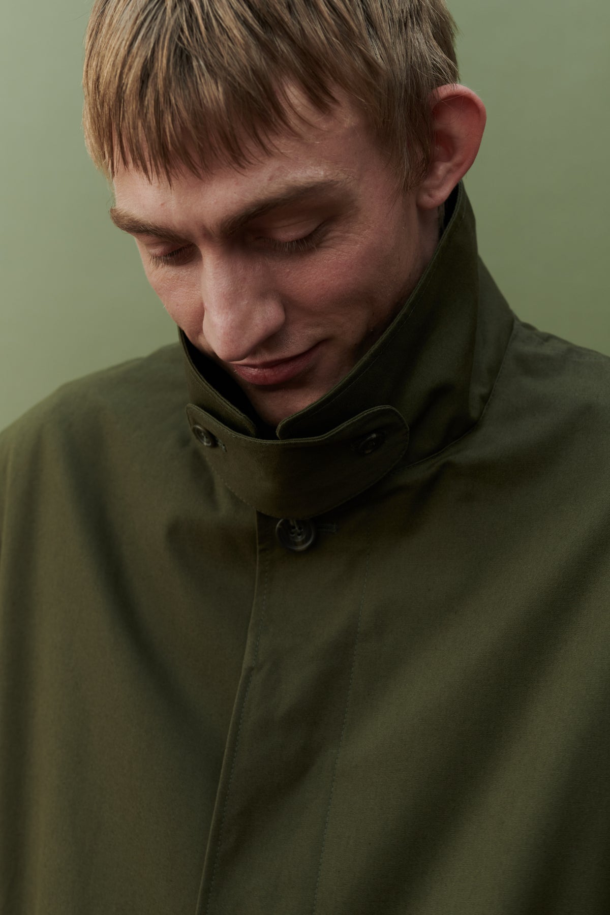 
            Image showing collar detail of men&#39;s raincoat in olive. Detachable collar strap.