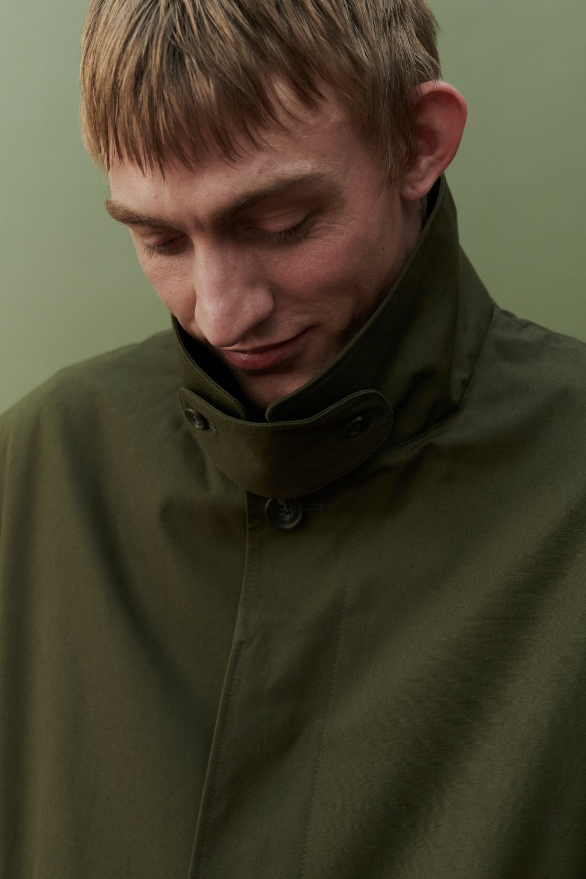 Image showing collar detail of men's raincoat in olive. Detachable collar strap.