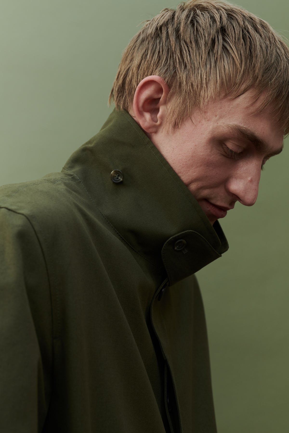 Image showing collar detail of men's raincoat in olive. Detachable collar strap
