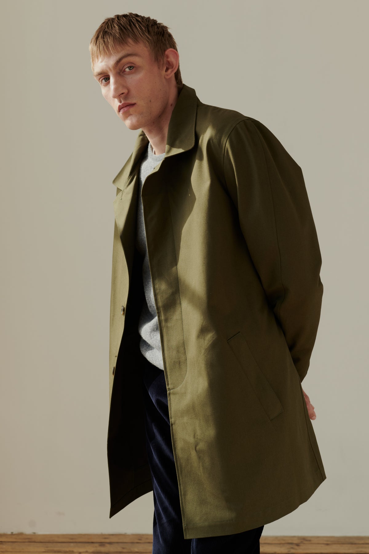 Thigh up image of male wearing men's raincoat in olive